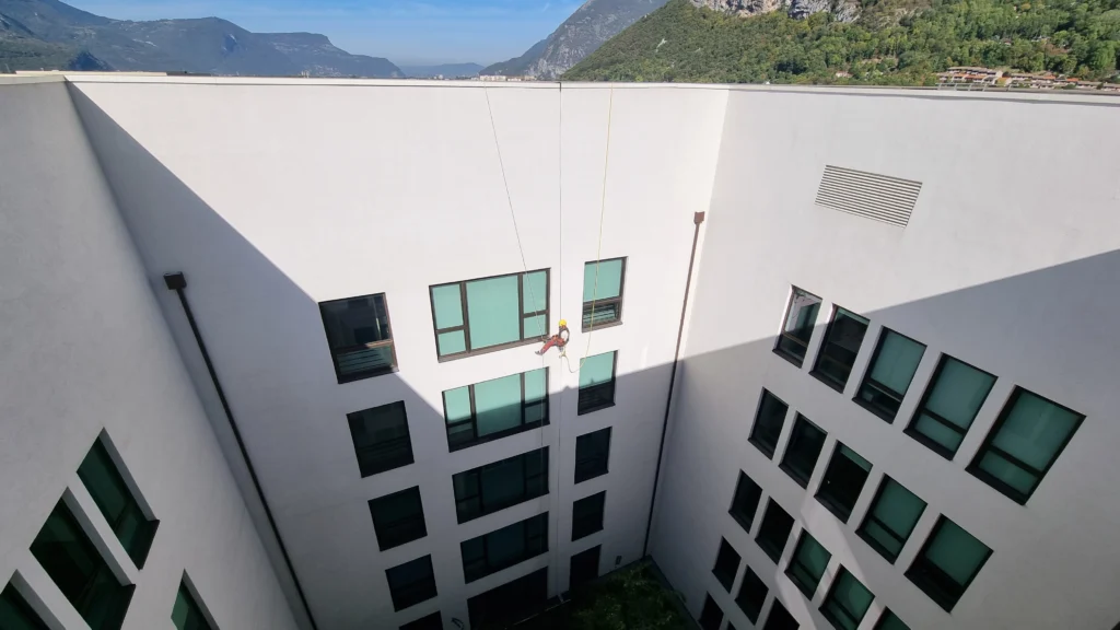 ouvrier cordiste qui effectue des travaux en hauteur sur une façade à Grenoble